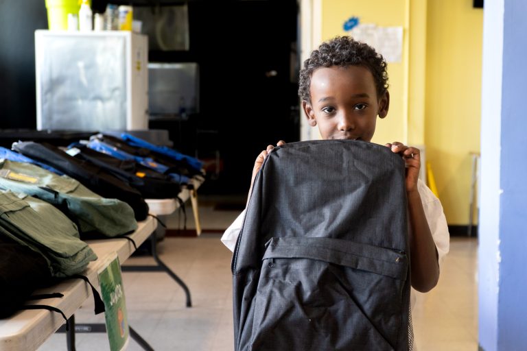A young tenant poses with their brand new backpack.